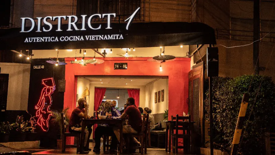 Fachada de District 1 de noche, con su aviso de Auténtica Cocina Vietnamita
